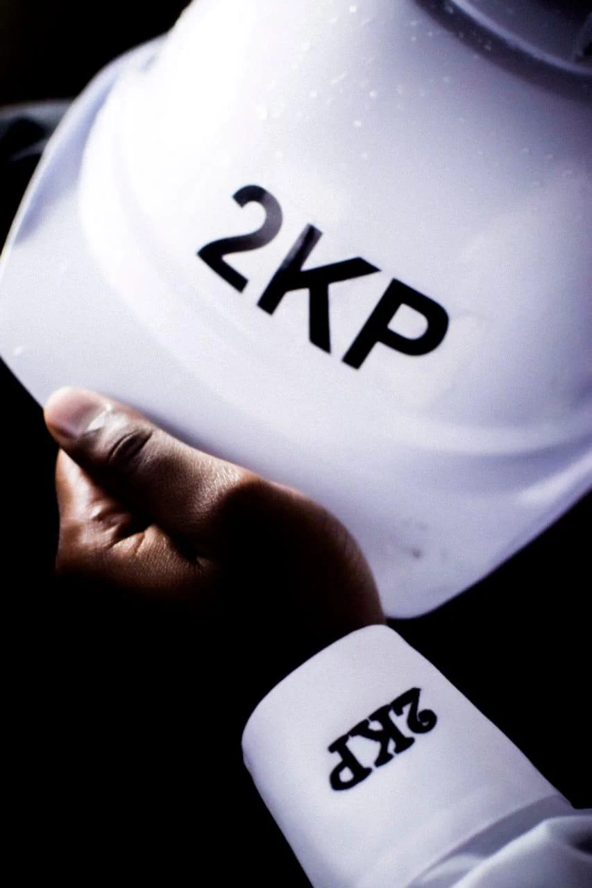 A 2KP-branded safety helmet held by a site worker